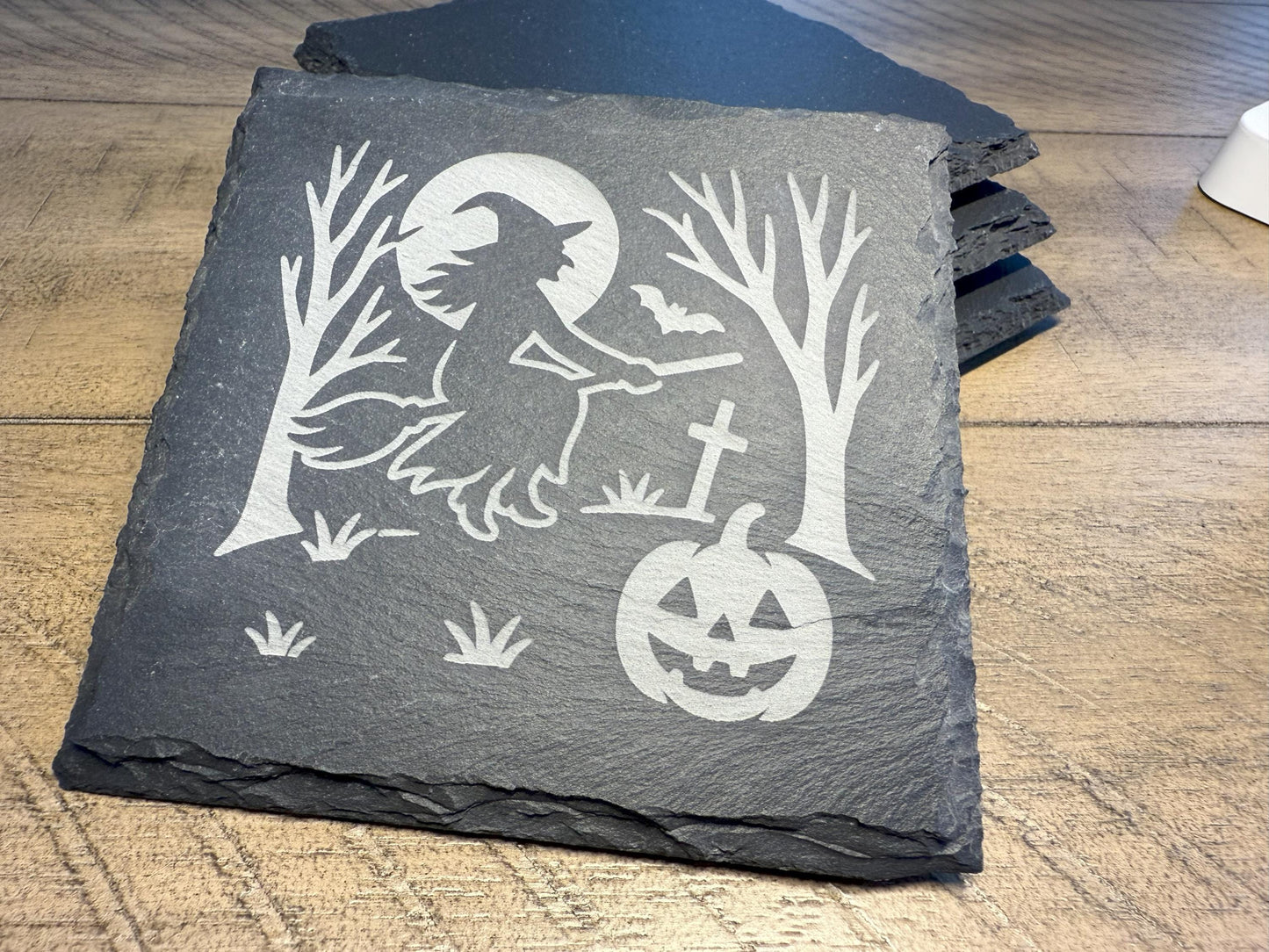 Slate coaster with Halloween design of a witch and pumpkin on a wooden surface