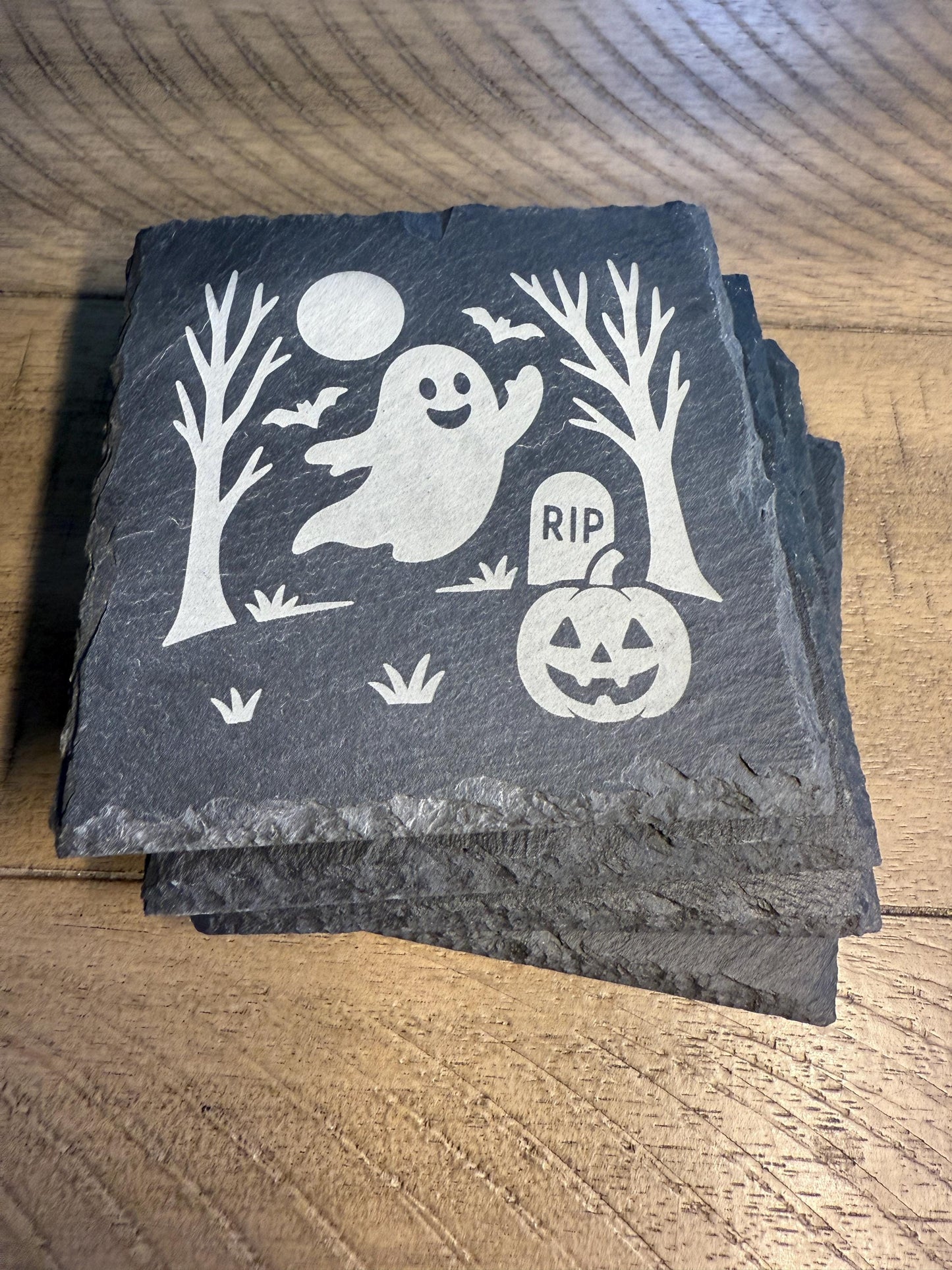Stack of Halloween-themed coasters with ghost, pumpkin, and tombstone design on a wooden surface.